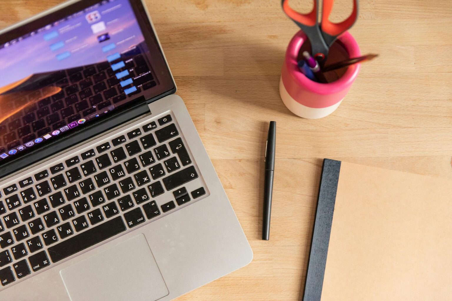 Modern laptop computer on wooden desk with coffee cup and notebook for social media management work