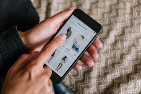 Person using smartphone to shop online, representing social commerce on mobile devices