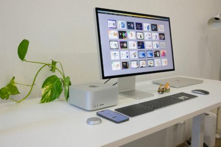 Clean modern workspace with computer displaying graphic design interface and creative tools