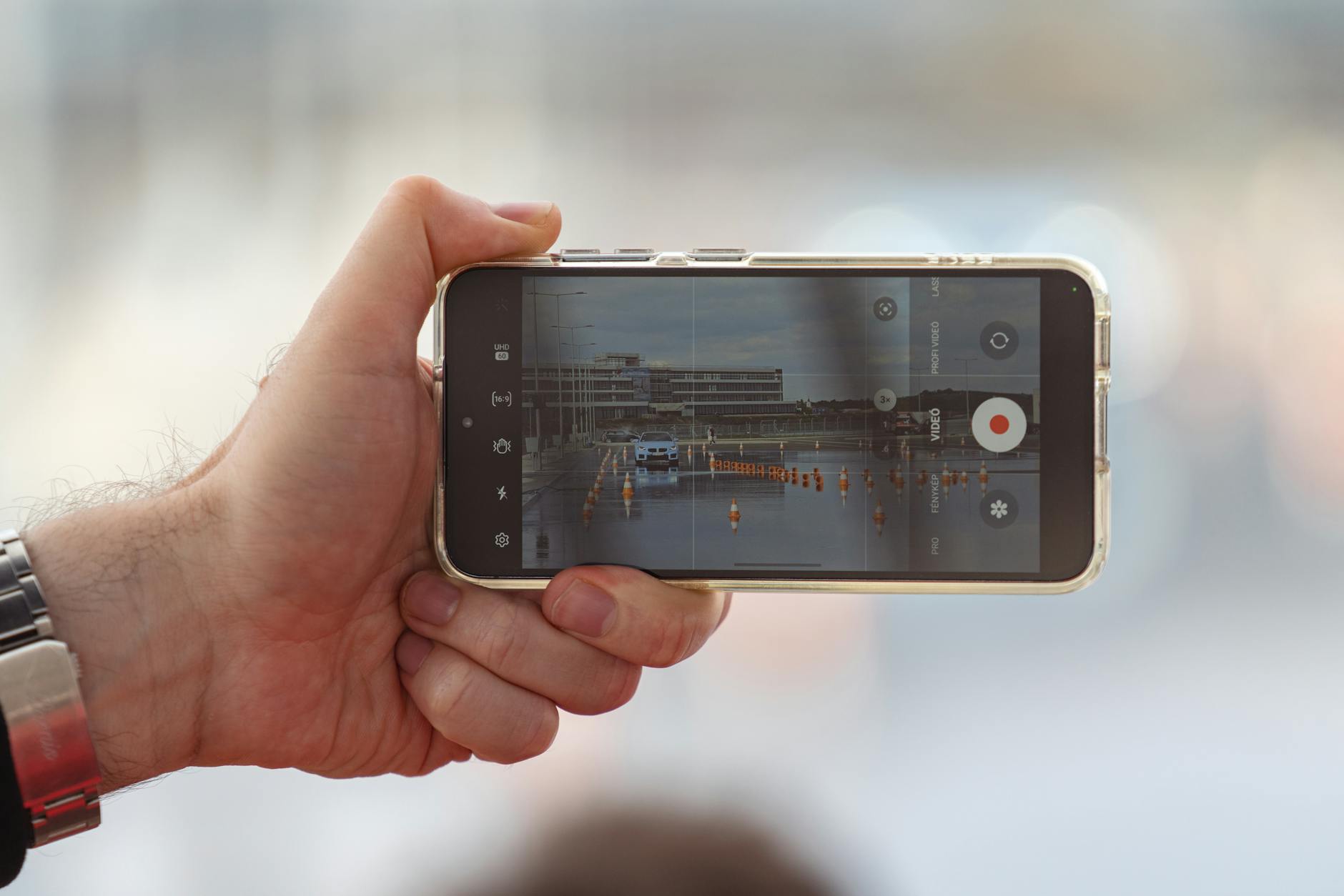 Person holding smartphone to record video content in bright lighting