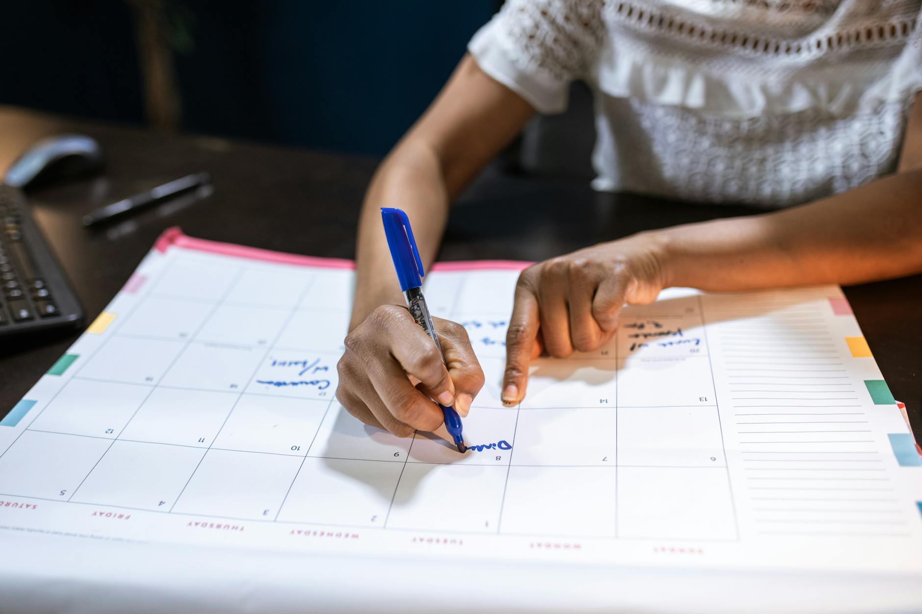 Person's hands marking dates on a calendar, representing daily habit tracking and streak maintenance