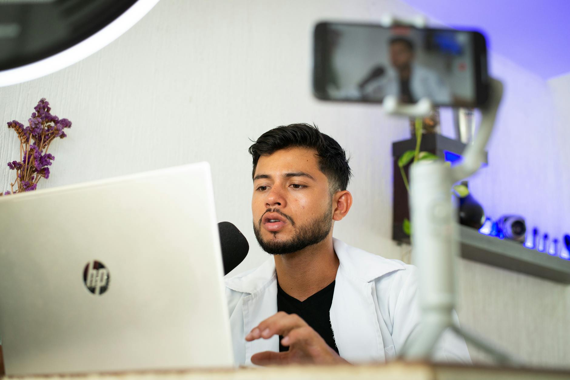 Person using laptop for live streaming with ring light and microphone setup