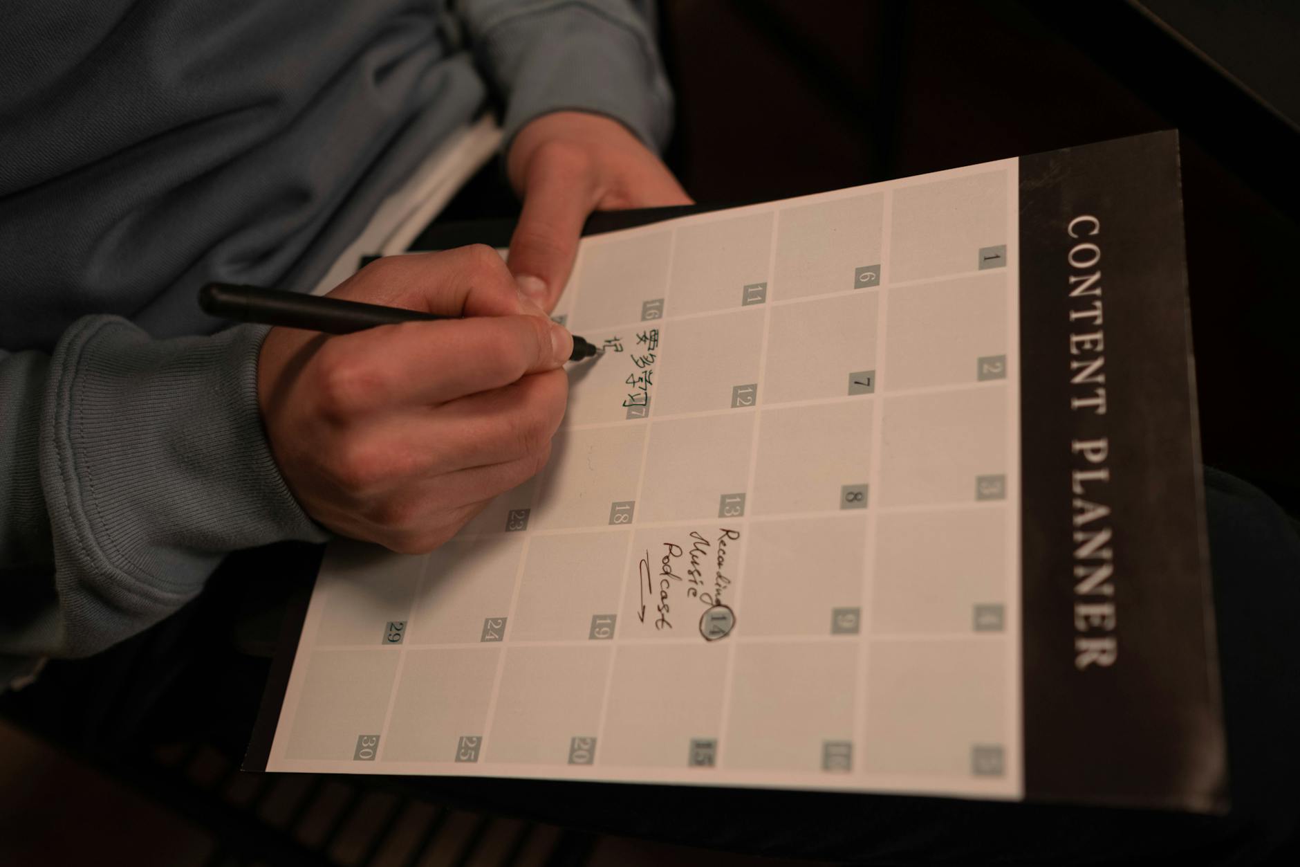 Person working on laptop creating digital content with notes and planning materials nearby