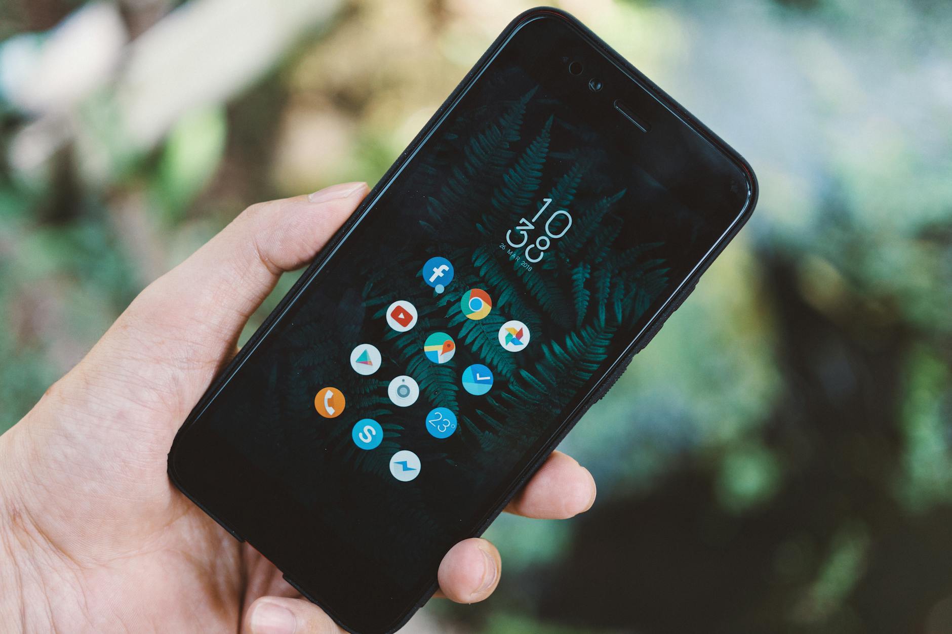 Hand holding smartphone displaying various social media app icons