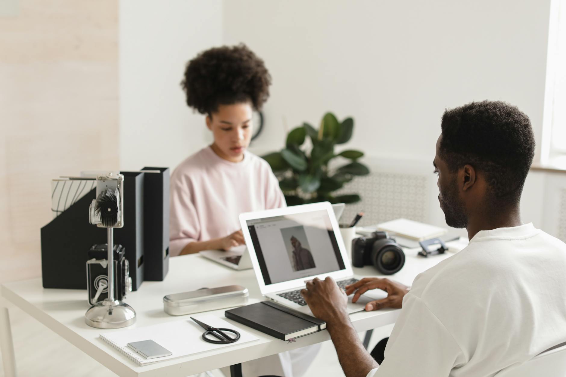 Content creator working at a desk with computer and camera setup