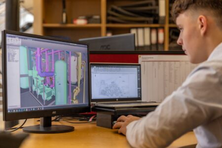 A designer working on a presentation layout on a desktop screen in a modern workspace