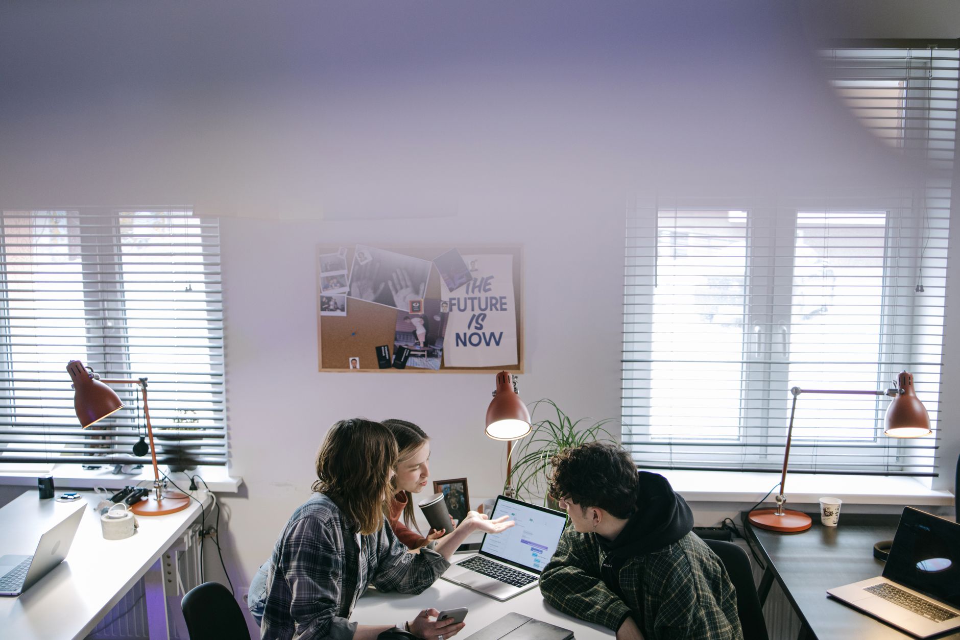 Two team members collaborating on a laptop screen showing a slide deck