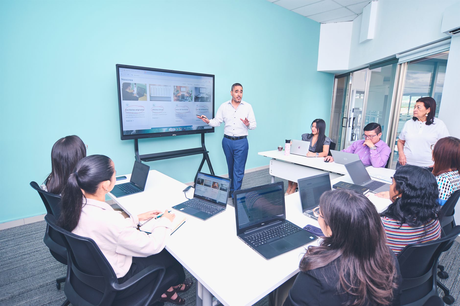 Marketing team members collaborating around a monitor reviewing a slide presentation