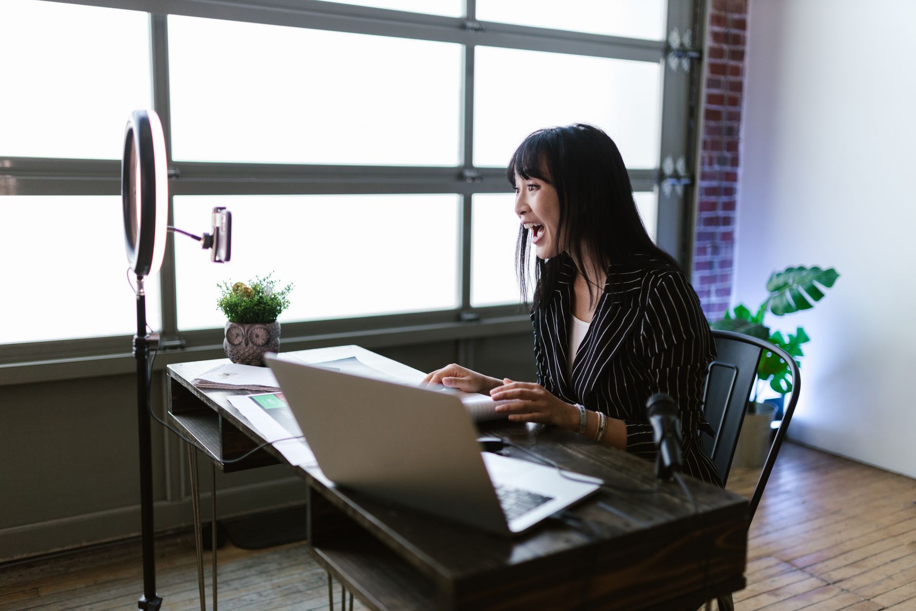 Creator working at a desk with phone and laptop managing social media accounts