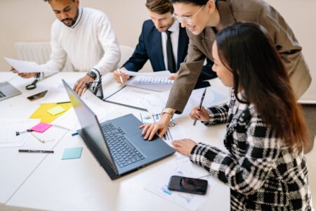 Marketing team members collaborating around a laptop in a modern office setting
