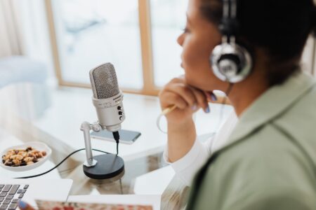 A professional podcast recording setup with microphone and computer screen in a home studio