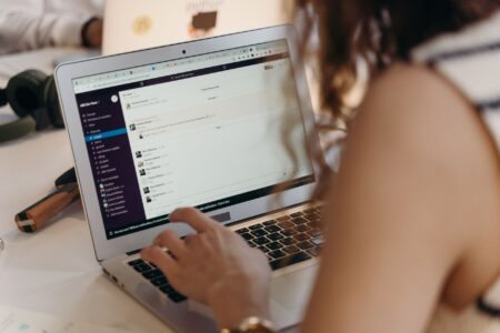 A person working at a desk managing email newsletters on a laptop